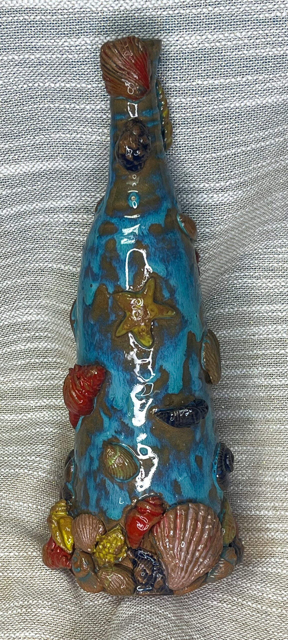 Ceramiczna butelka zdobiona w morskie motywy muszli i rybek